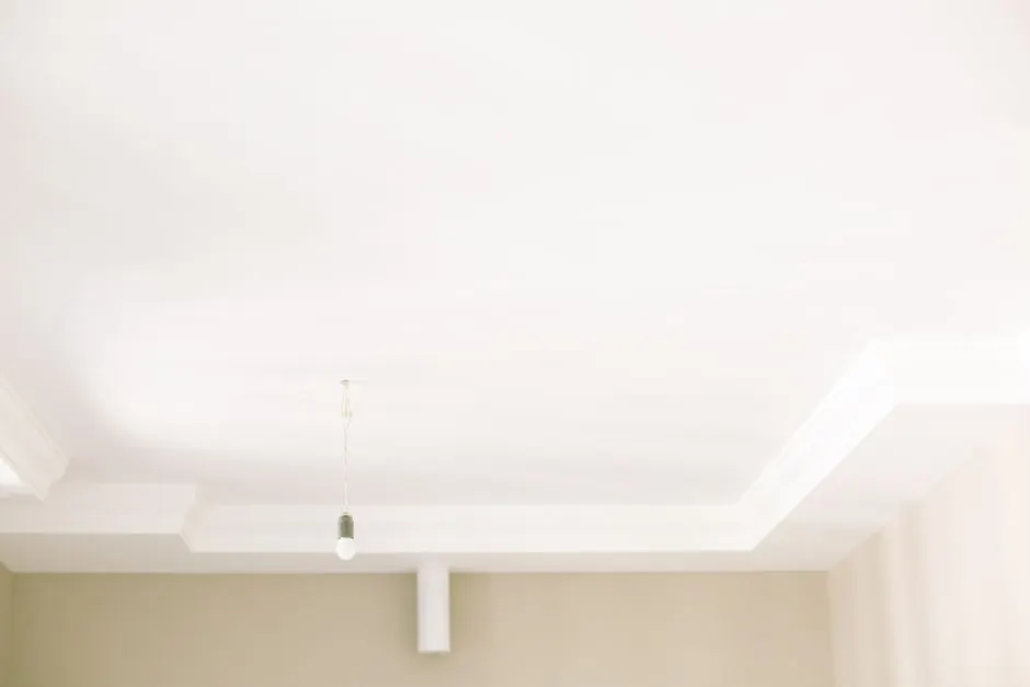 Bright white ceiling with a single hanging light bulb highlighting minimal interior design.
